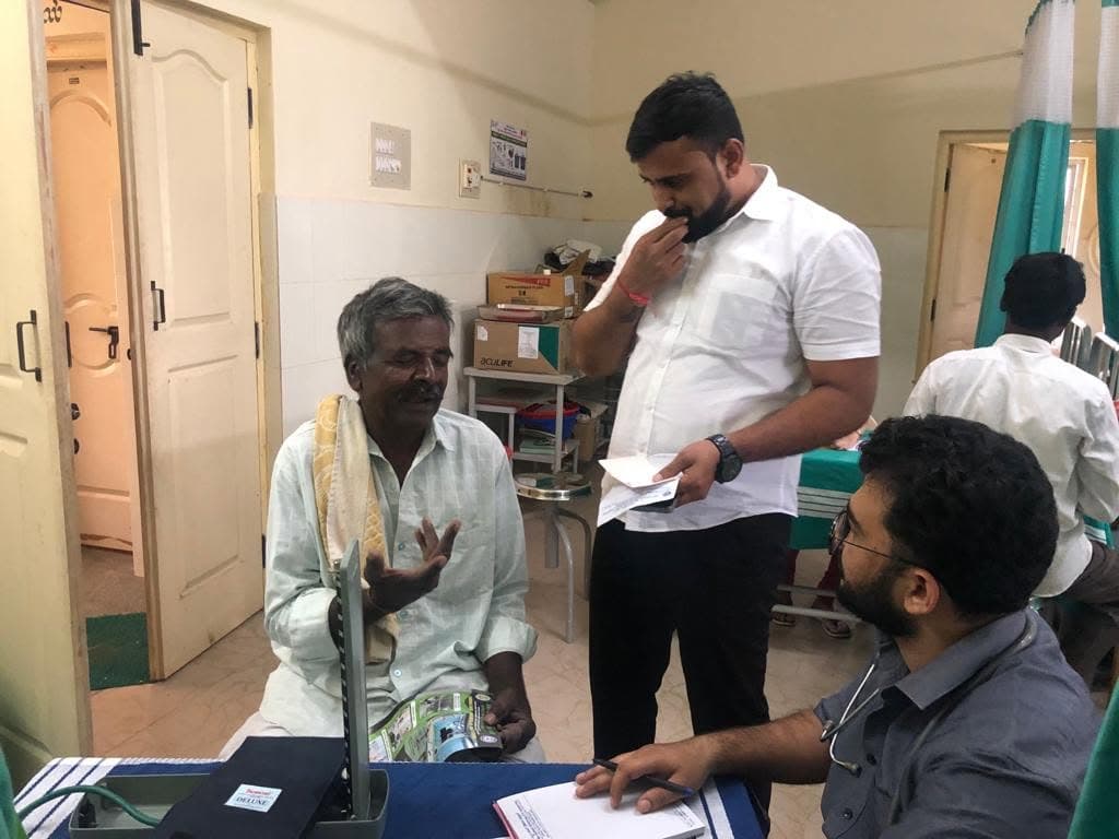 A doctor checking an elderly patient's blood pressure at a free health checkup camp.