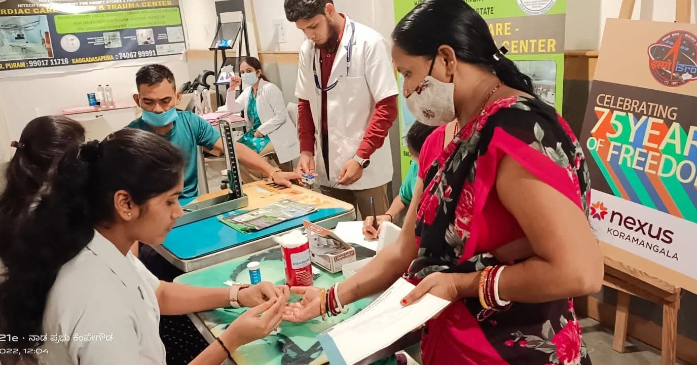 Hospital staff checking a visitor's blood sugar at a free health camp booth at Nexus Mall, Koramangala.