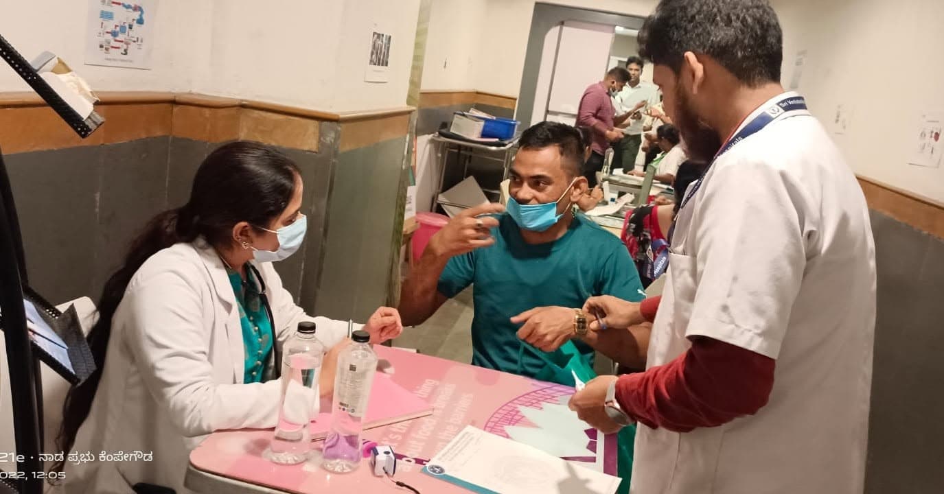 A doctor attending to a patient at an indoor health camp registration desk.