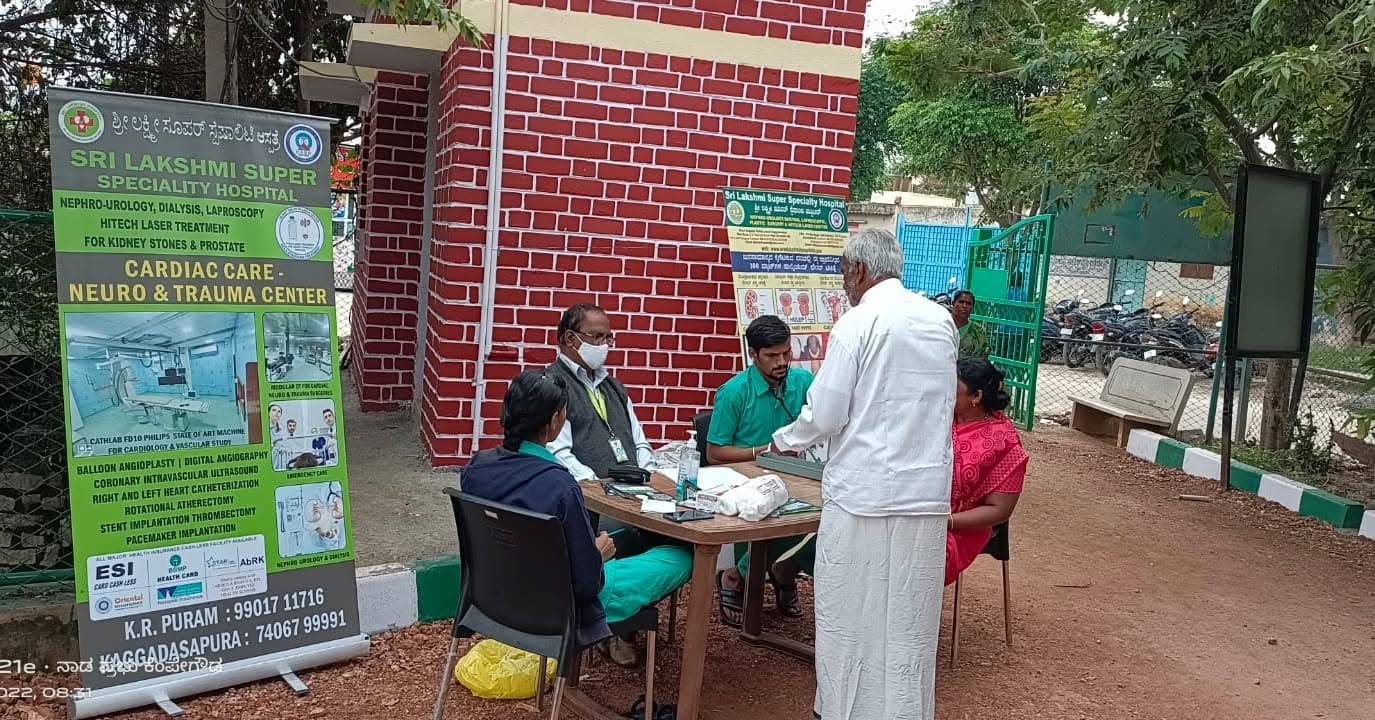 Hospital staff attending to visitors at an outdoor free health camp booth.